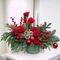Red and green Christmas flower arrangement in a glass vase