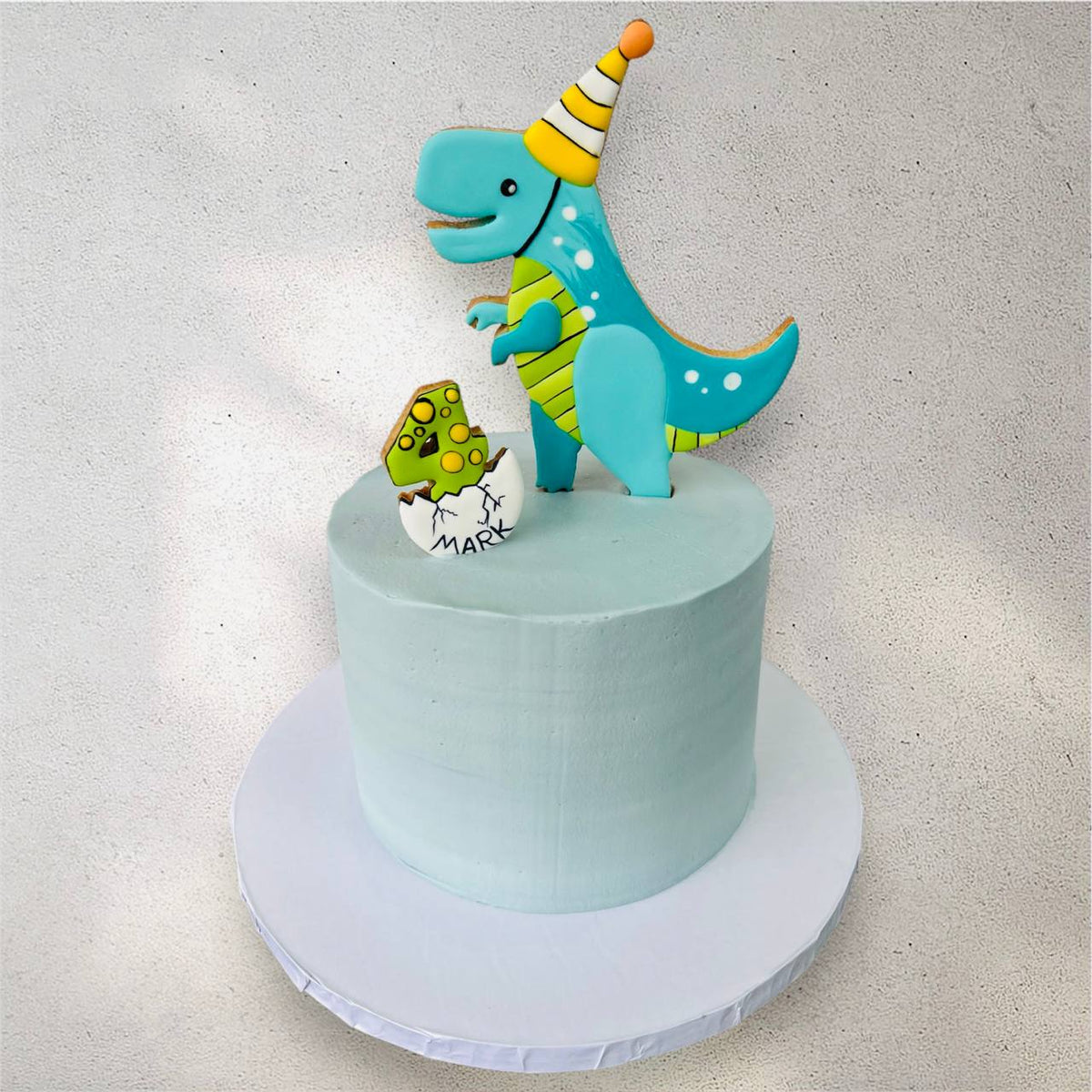 Dinosaur birthday cake with a roaring T-rex and jungle scene design
