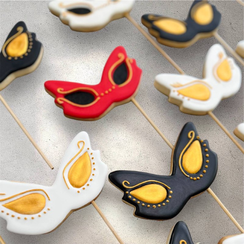 Masquerade mask cookies decorated with intricate icing patterns