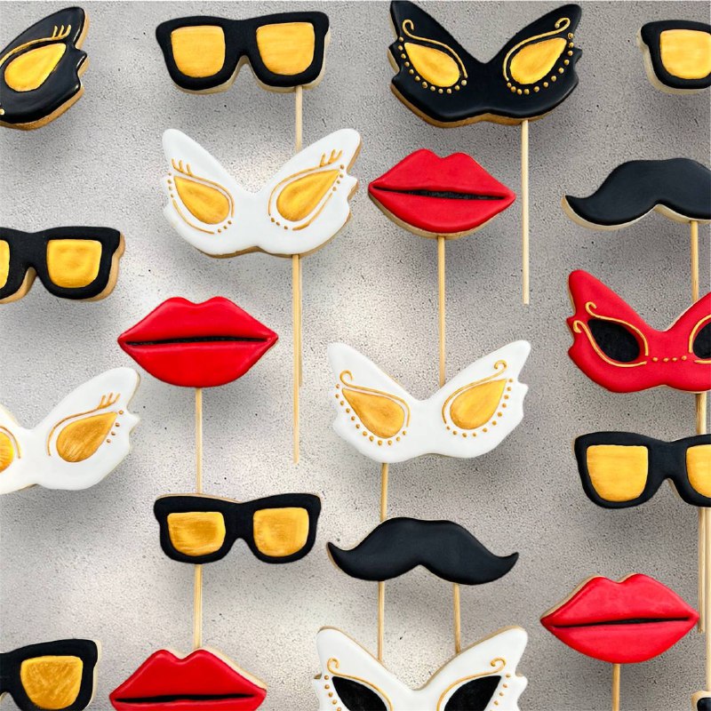 Decorated cookies shaped like ornate masquerade masks in gold and black