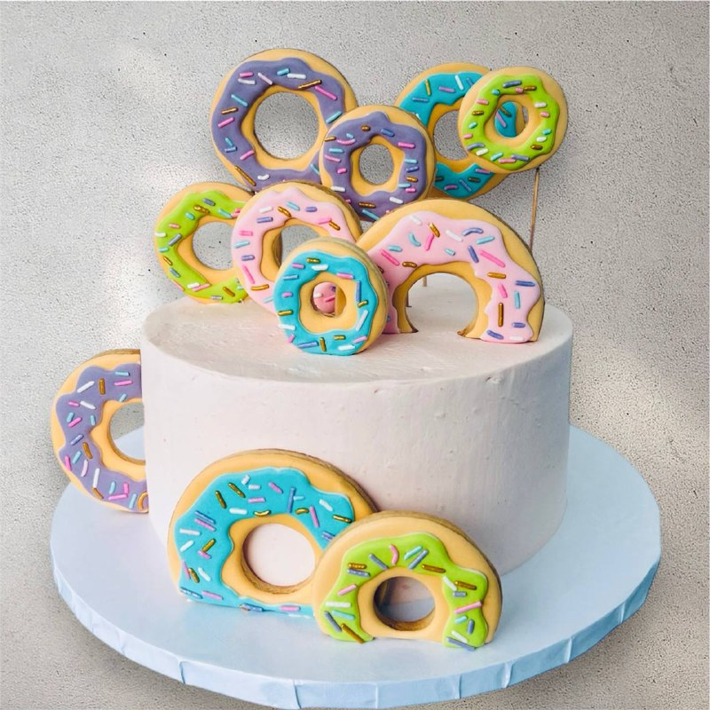 White buttercream cake topped with assorted mini donuts and rainbow sprinkles