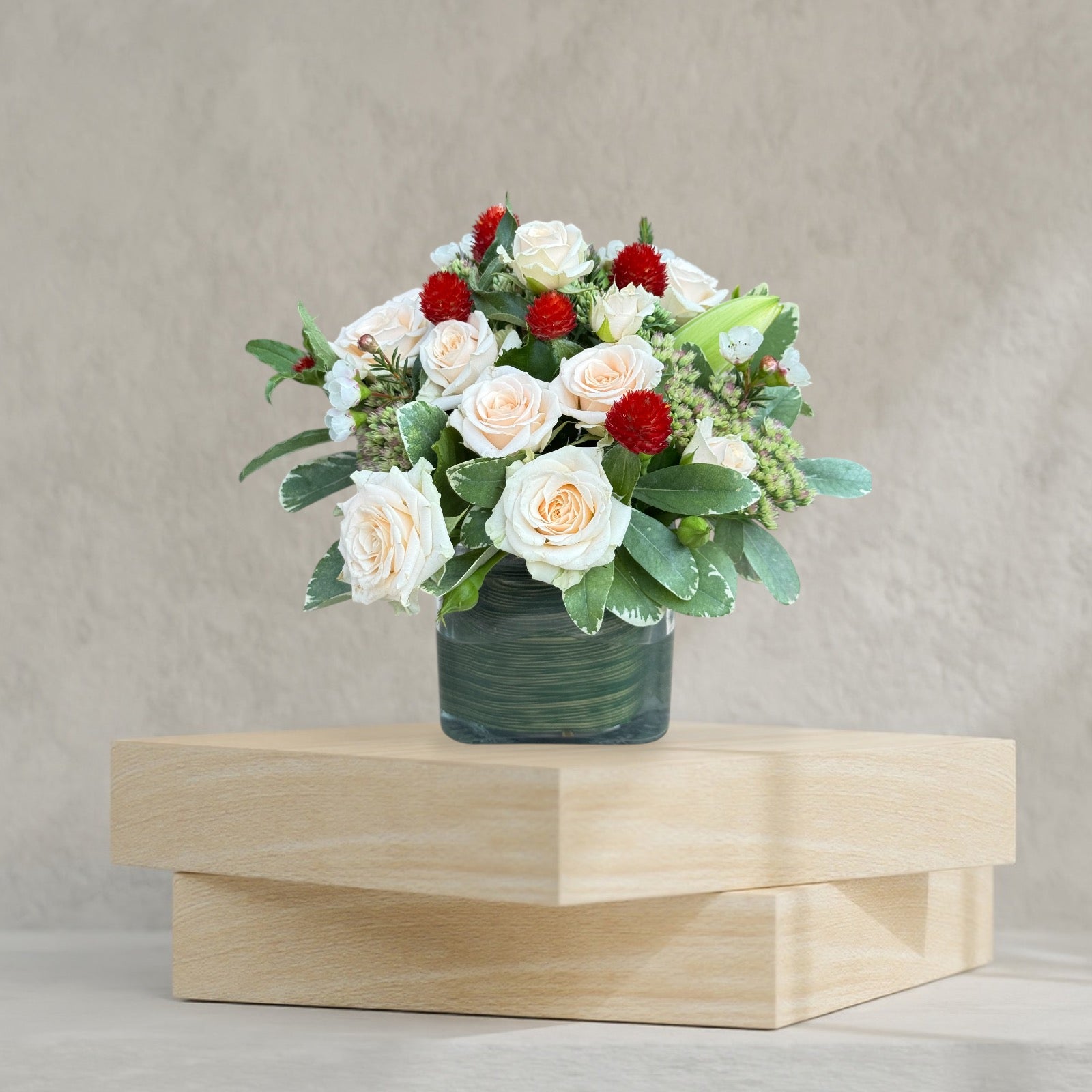 Small vase arrangement with warm orange and red toned flowers