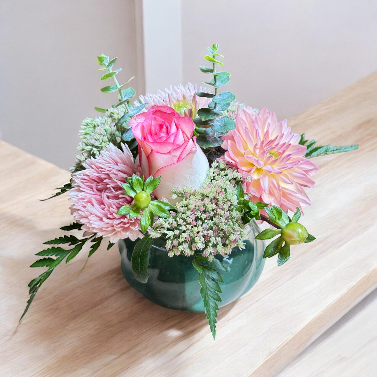 Colourful mixed flower arrangement in a vase with green foliage