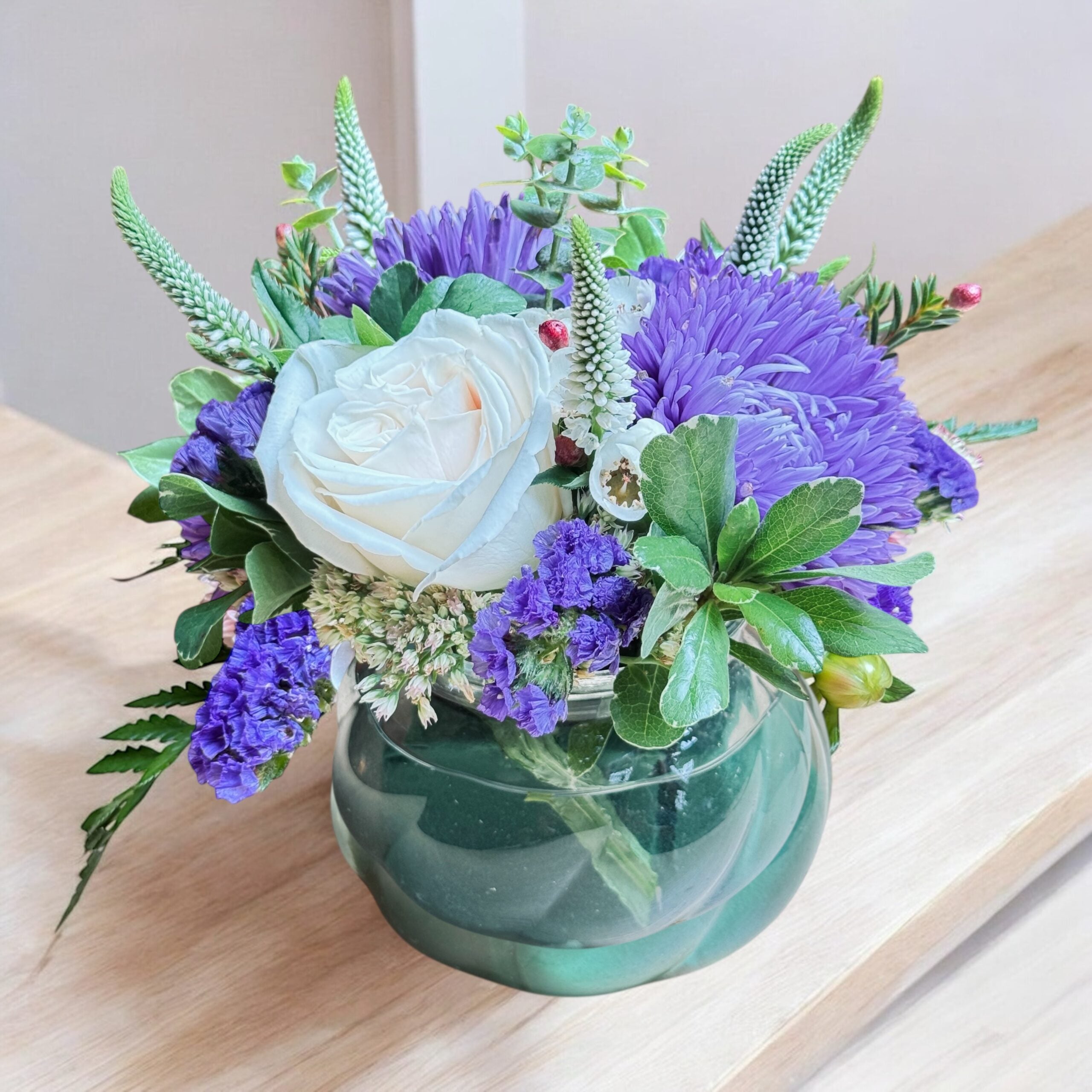 Bright vase arrangement with light-toned flowers and greenery