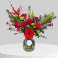 Deep red holiday flower arrangement in a vase with seasonal greenery