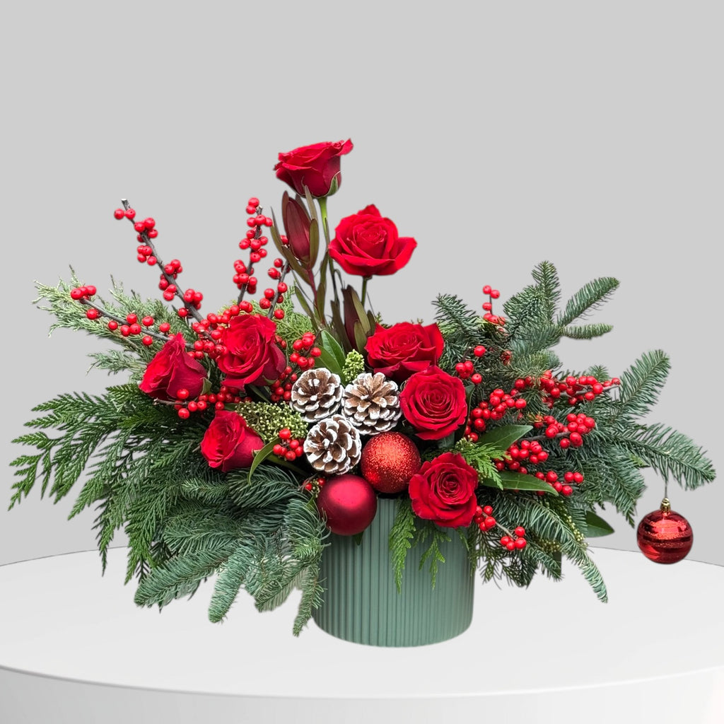 Close-up of holiday floral arrangement with pine accents and red blooms