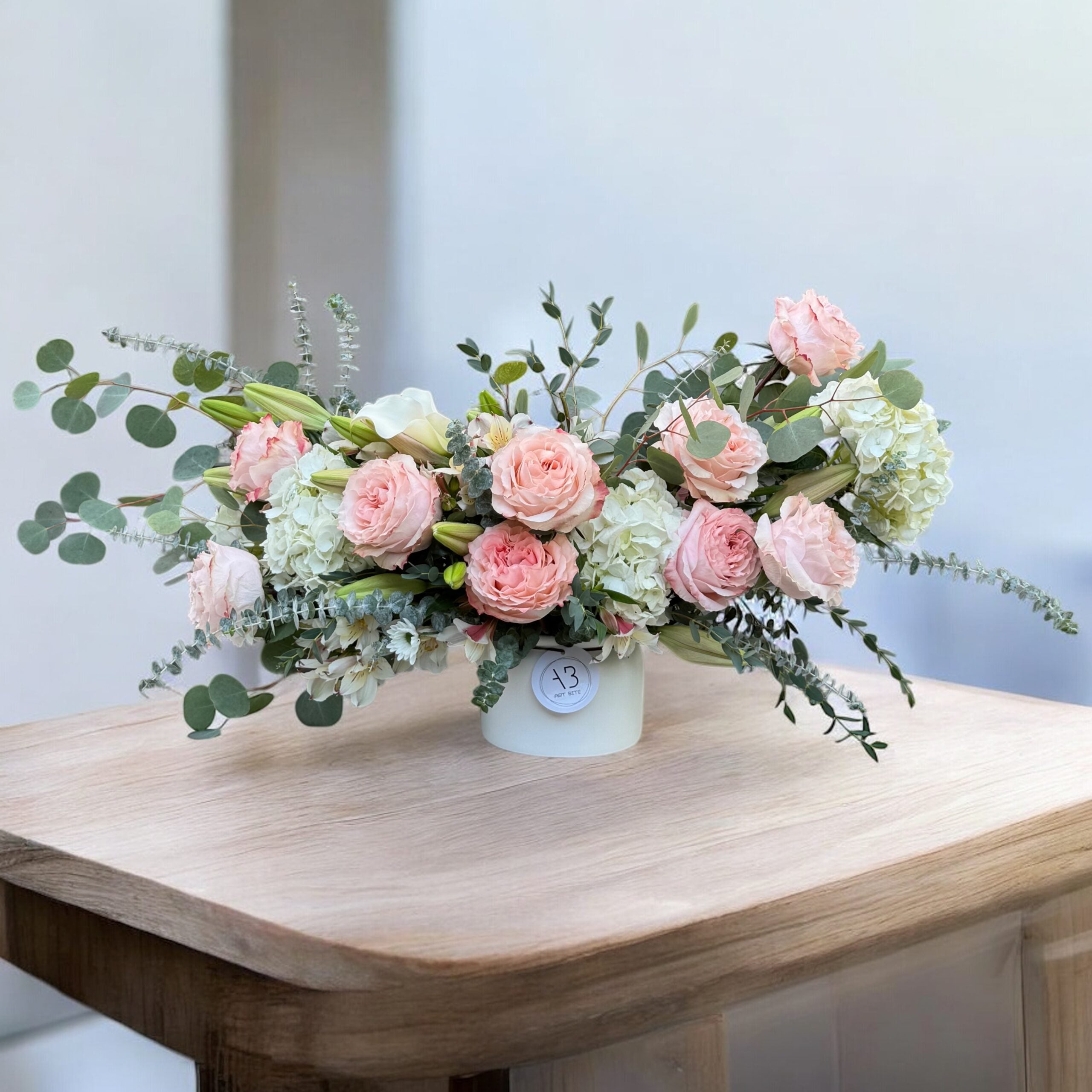 Close-up of pink blooms and greenery in a vase arrangement