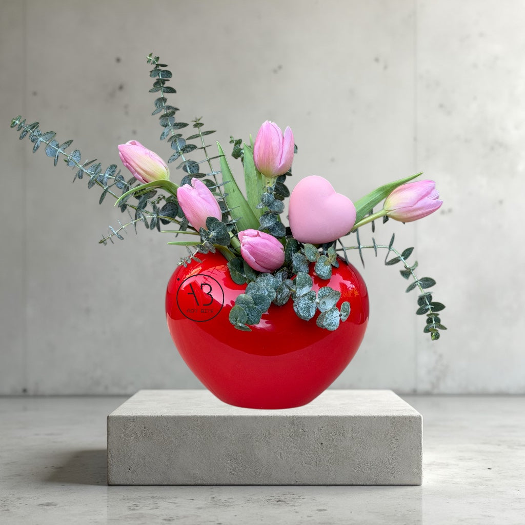 Deep red rose vase arrangement with lush green foliage