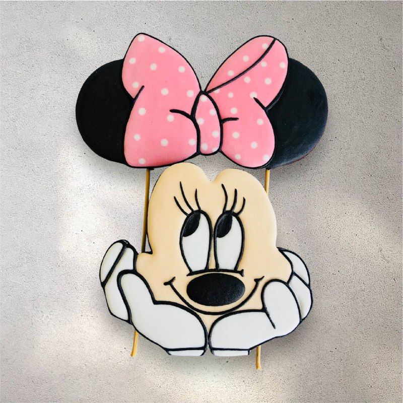 Pink decorated Minnie Mouse cookies used as a birthday cake topper